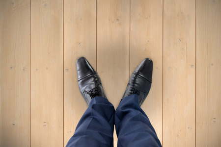 Businessman standing isolated on white background against wooden planksの写真素材
