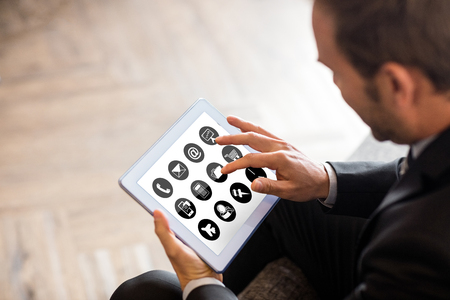 Telephone with apps icon  against businessman using tabletの写真素材