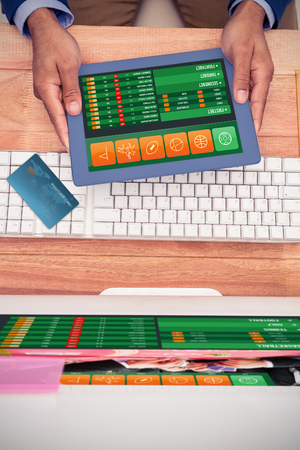 World credit card against businessman holding digital tablet by keyboard at deskの写真素材