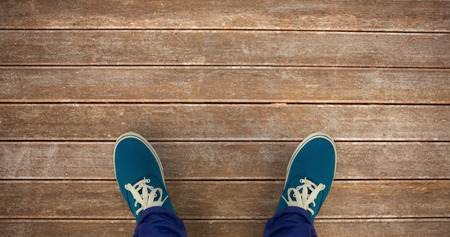 Man with canvas shoes on hardwood floor against wooden planks background