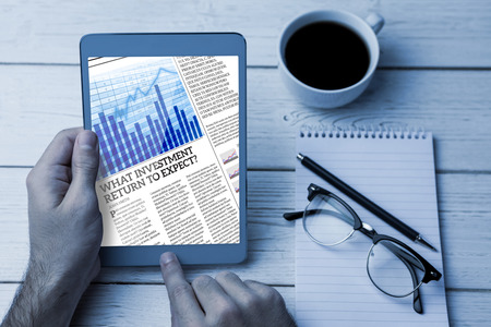 Business newspaper  against cropped image of person using tablet computer