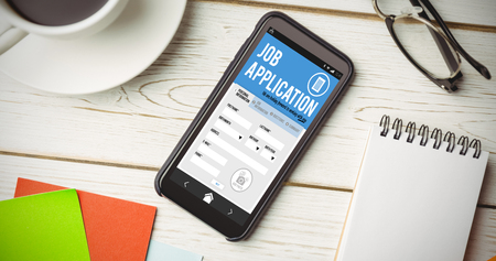 Job application on smartphone   against overhead view of an deskの写真素材