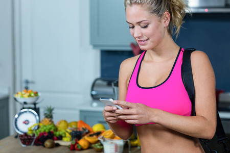 Fit girl texting in the kitchenの写真素材