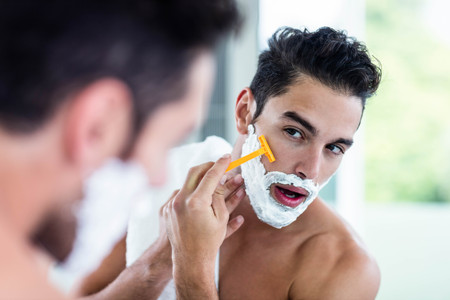 Handsome man shaving his beard in bathroomの写真素材