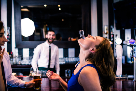 Woman playing with her shot in a bar with friends