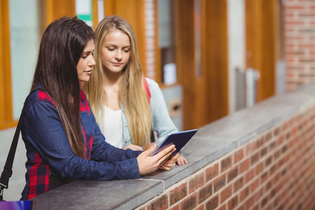 Smiling students using tablet together at universityの写真素材