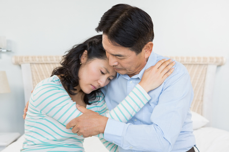 Sad couple embracing at homeの写真素材