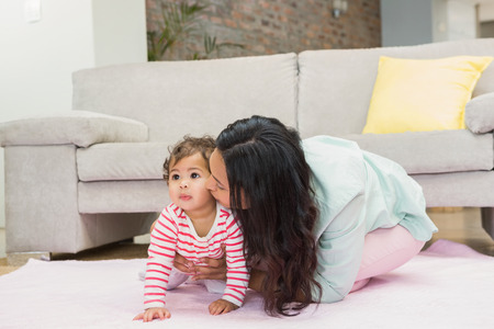Happy mother with her baby daughter on the carpet in living room
