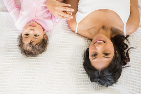 Brunette playing with her baby on the bedの写真素材