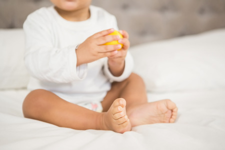 Cute baby playing with ball on bed