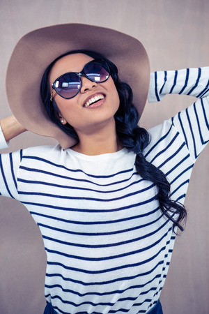 Smiling Asian woman with hat and sunglasses posing for cameraの写真素材
