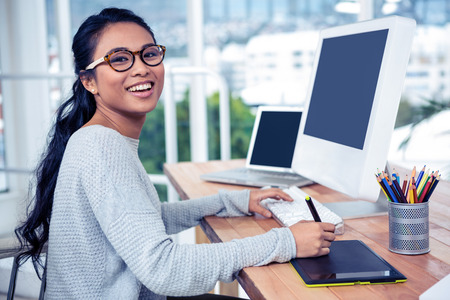 Smiling Asian woman using digital board and computer in officeの写真素材
