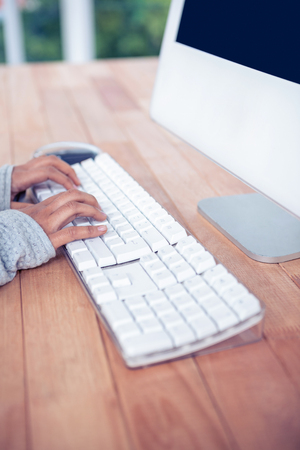 Womans hands typing on computer keyboard in officeの写真素材