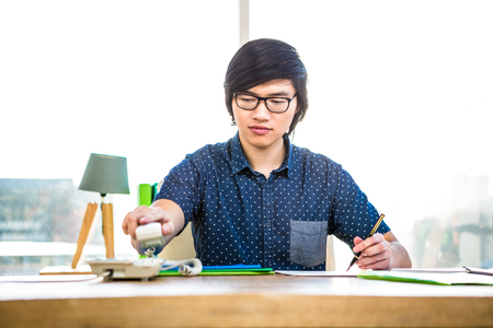 Smiling hipster businessman writing in officeの写真素材
