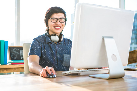 Smiling asian businessman using computer in officeの写真素材
