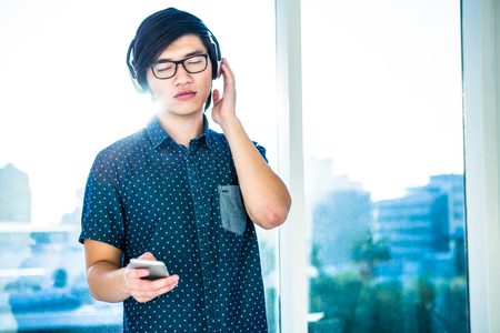 Concentrated asian businessman listening to music in officeの写真素材