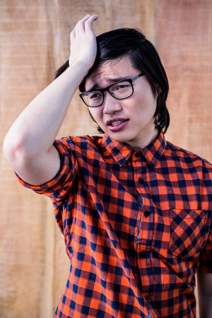 Sad hipster holding his head with his hand on wooden backgroundの写真素材