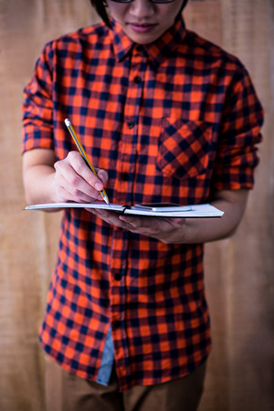 Hipster taking notes on notebooks on wooden backgroundの写真素材