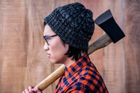 Side view of hipster holding a axe on wooden backgroundの写真素材
