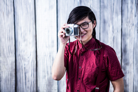 Hipster taking pictures with an old camera on wooden background