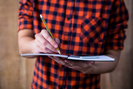 Hipster taking notes on notebooks on wooden backgroundの写真素材