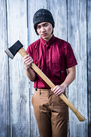 Hipster holding a axe on wooden backgroundの写真素材