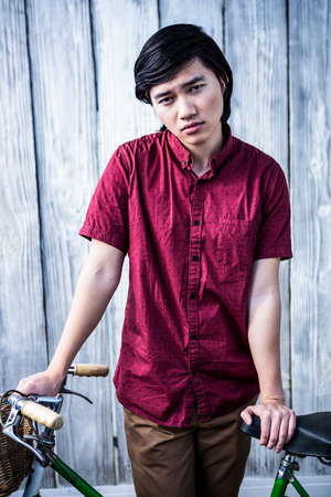 Hipster man holding a bike on wooden backgroundの写真素材