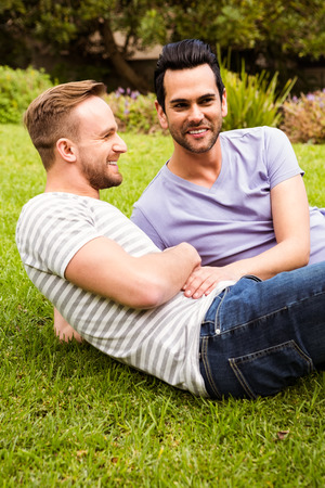 Happy gaycouple lying on grass in gardenの写真素材