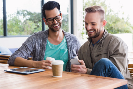 Designers with take-away coffee using smartphone at the office