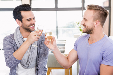 Smiling gay couple toasting with champagne at homeの写真素材