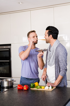 Smiling man tasting soup in the kitchenの写真素材