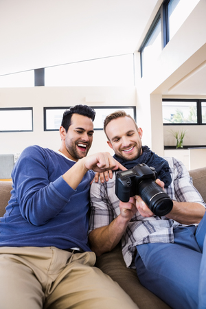 Gay couple watching pictures on the couch in the living roomの写真素材