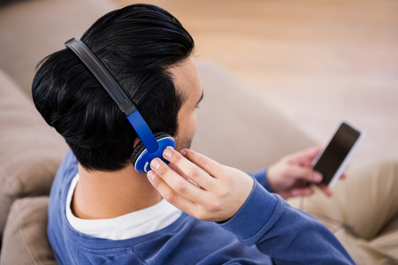Man listening to music with headphones on the couchの写真素材