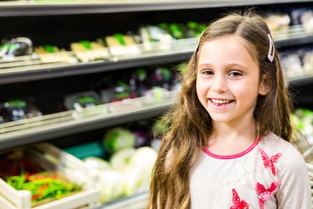 Cute girl smiling at the camera in the grocery storeの写真素材