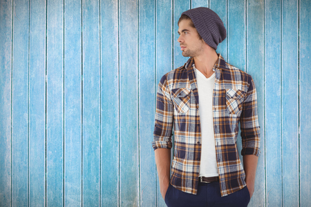 Confident hipster looking away while standing against wooden planksの写真素材