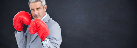 Tough businessman with boxing gloves against blackboardの写真素材