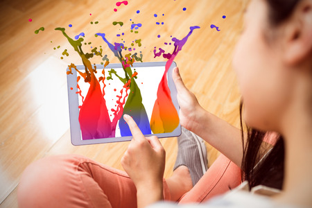 Pink paint splashes and drops against girl using her tablet