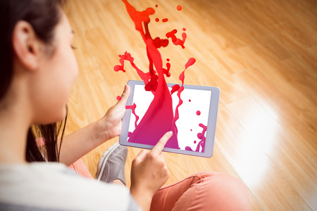 Pink paint splashes and drops against girl using her tablet
