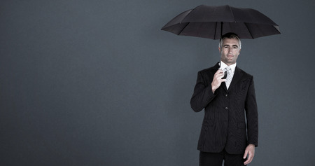 Businessman holding umbrella on white background against grey backgroundの写真素材