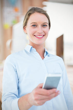 Composite image of businesswoman using her mobile phoneの写真素材