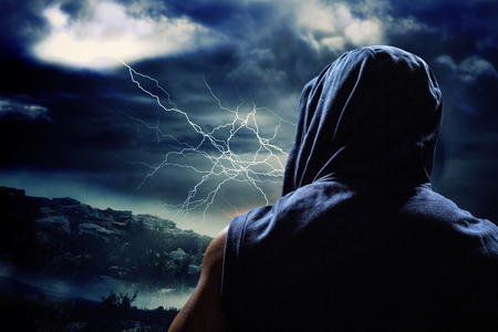 Rear view of athlete against stormy sky with tornado over landscapeの写真素材
