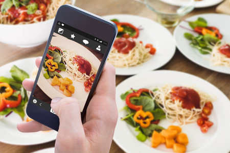 Woman using her mobile phone against healthy mealの写真素材