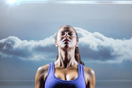 Fit woman meditating against black background against clouds in a roomの写真素材