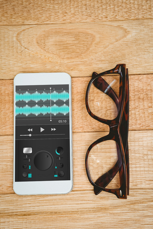 Music app against view of glasses and a smartphoneの写真素材