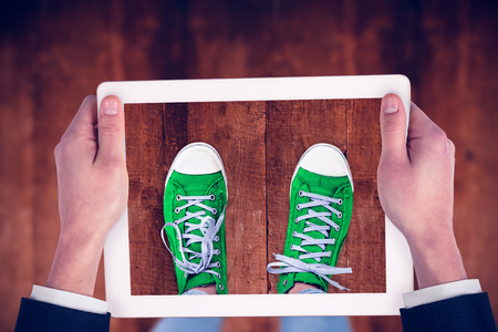 Feminine hands holding tablet against weathered oak floor boards backgroundの写真素材