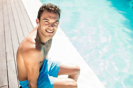 Handsome man resting on the edge of the poolの写真素材