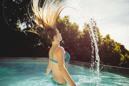 Beautiful blonde heading out of water in the poolの写真素材