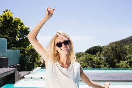 Beautiful blonde smiling at the camera by the poolの写真素材