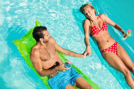 Peaceful couple on lilos holding cocktails in the pool