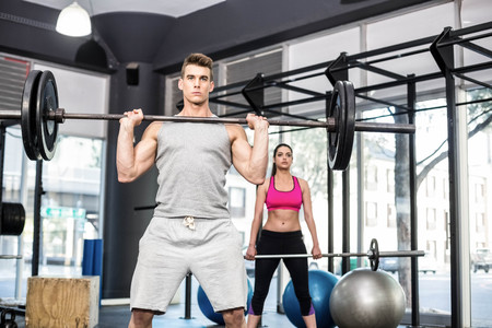 Fit couple lifting barbell at crossfit gymの写真素材